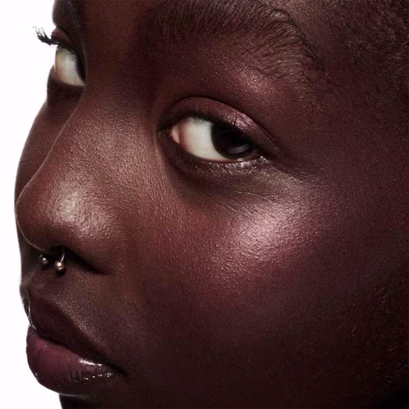 A imagem mostra uma modelo de pele retinta e o efeito de cor do Blush Líquido M·A·C Strobe Nitelite