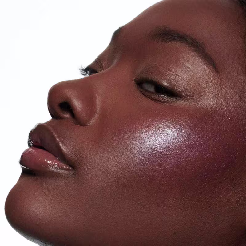A imagem mostra uma modelo de pele retinta e o efeito de cor do Blush Líquido M·A·C Strobe Magic Aura