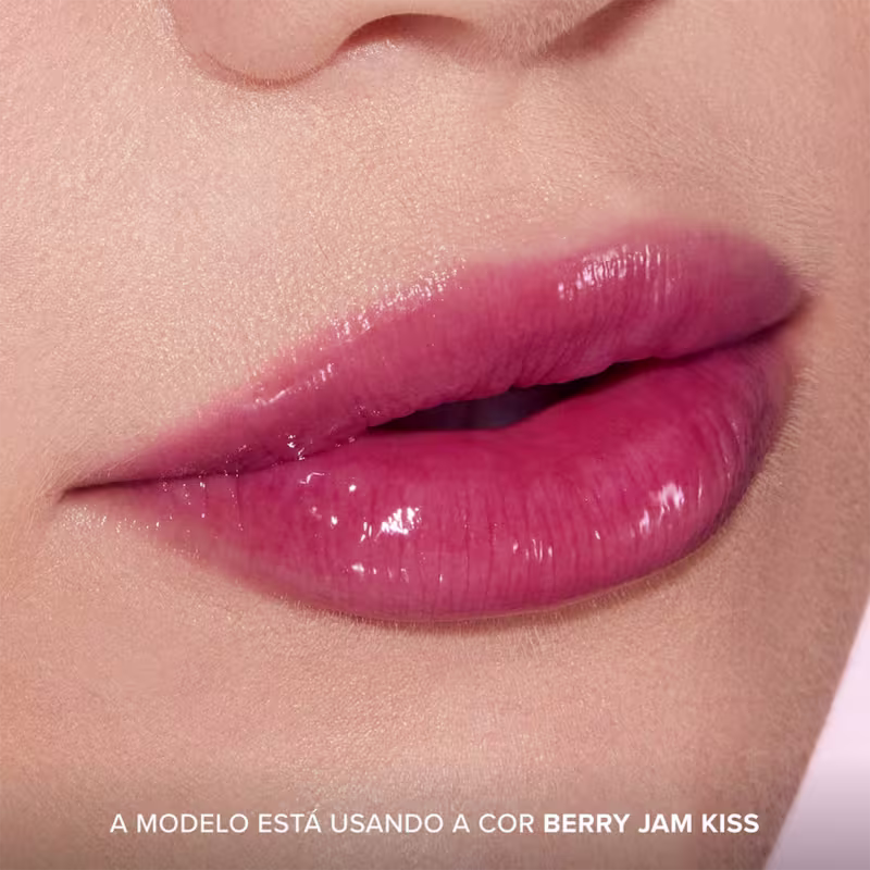 A imagem mostra o resultado do uso do Lip Treatment Too Faced Pillow Balm, com foco nos lábios. Frase: A modelo está usando a cor Berry Jam Kiss