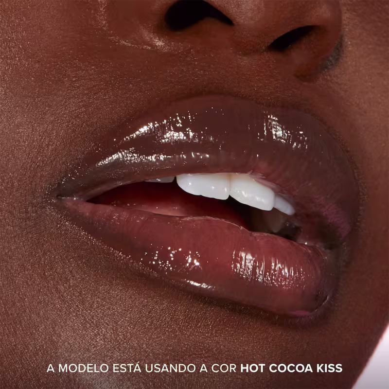 A imagem mostra o resultado do uso do Lip Treatment Too Faced Pillow Balm, com foco nos lábios. Frase: A modelo está usando a cor Hot Cocoa Kiss