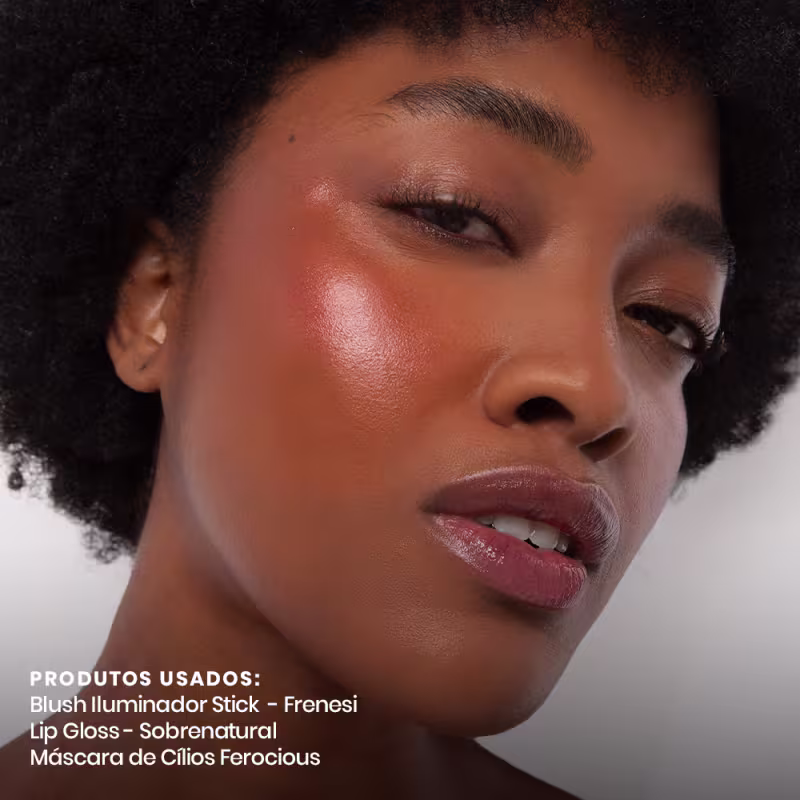 A imagem mostra uma modelo maquiada com blush iluminador em bastão Frenesi, gloss labial Sobrenatural e máscara de cílios Ferocious, todos da Contém1g