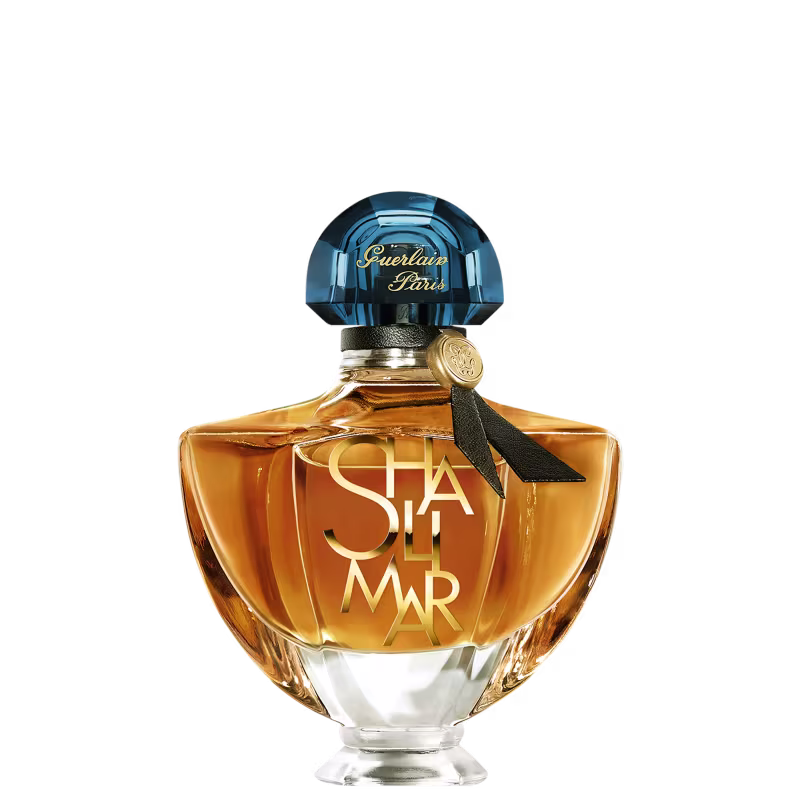 Frasco de perfume Guerlain Paris com tampa de cristal azul e rótulo dourado com a inscrição "Shalimar". Embalagem de vidro âmbar com design elegante e clássico.