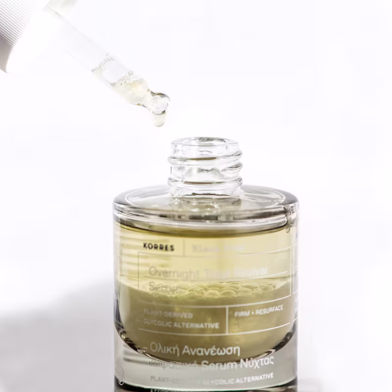Frasco de vidro transparente contendo um líquido amarelado, com rótulo da marca Korres indicando um produto de cuidados com a pele, com informações sobre o tipo de produto e suas propriedades.