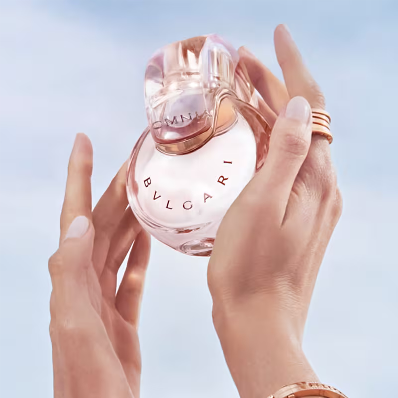 Frasco de perfume Omnia da marca Bvlgari, com formato oval e tampa transparente, exibindo o nome da marca em letras douradas. 