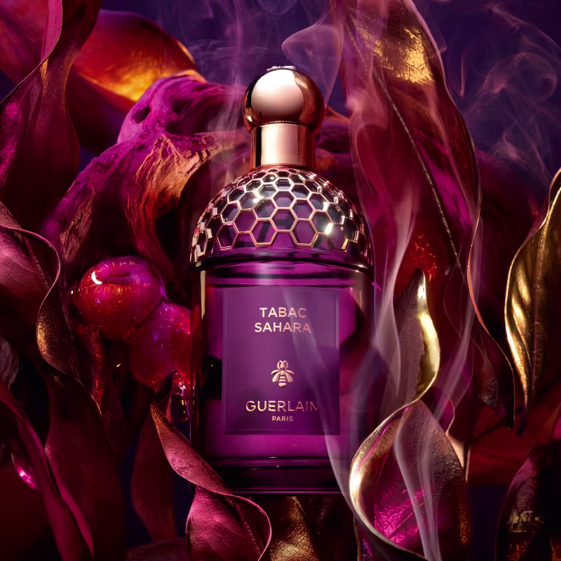 Frasco de perfume Guerlain Tabac Sahara, com design elegante e geométrico em tons de roxo e dourado, destacando o nome da fragrância e a marca.
