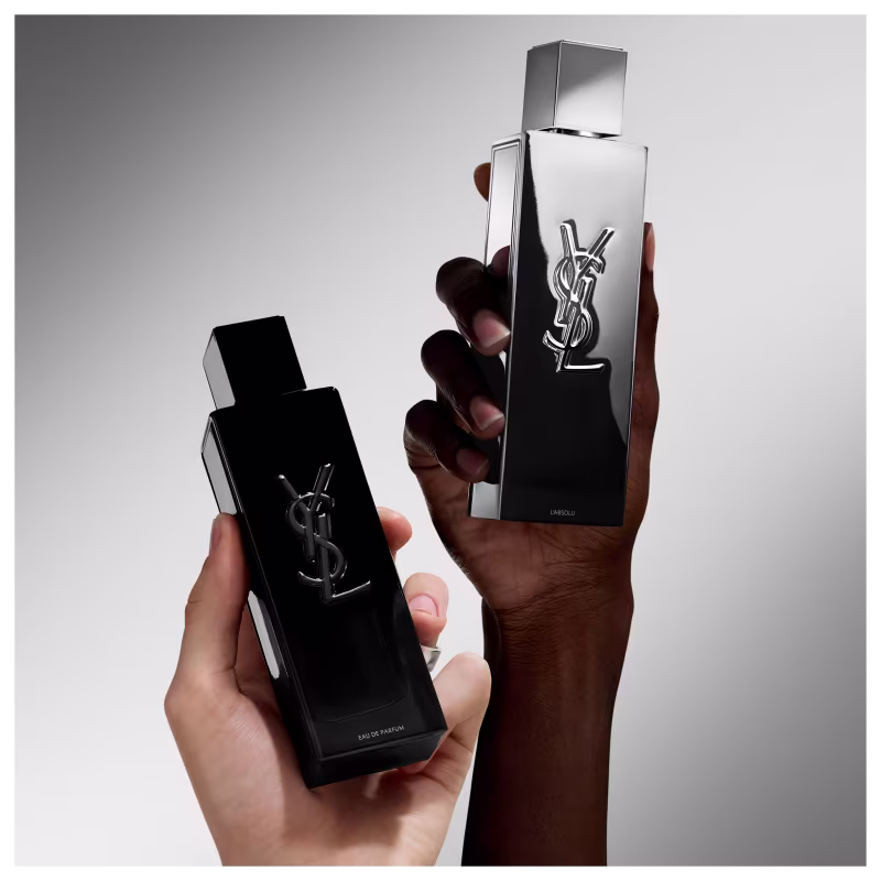 Frasco de perfume de design minimalista prateado, com o logotipo da marca Yves Saint Laurent em destaque. A embalagem possui uma forma geométrica simples e elegante, com uma tampa destacada no topo.