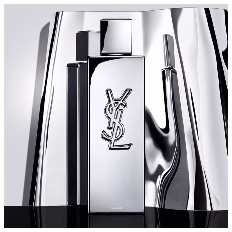 Frasco de perfume de design minimalista prateado, com o logotipo da marca Yves Saint Laurent em destaque. A embalagem possui uma forma geométrica simples e elegante, com uma tampa destacada no topo.