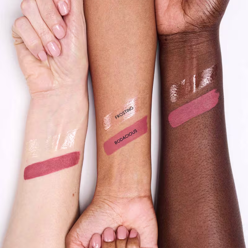 A imagem mostra diferentes tons de pele com marcas de produtos de beleza, como "Frosting" e "Bodacious", em um ambiente de teste ou demonstração de cosméticos.
