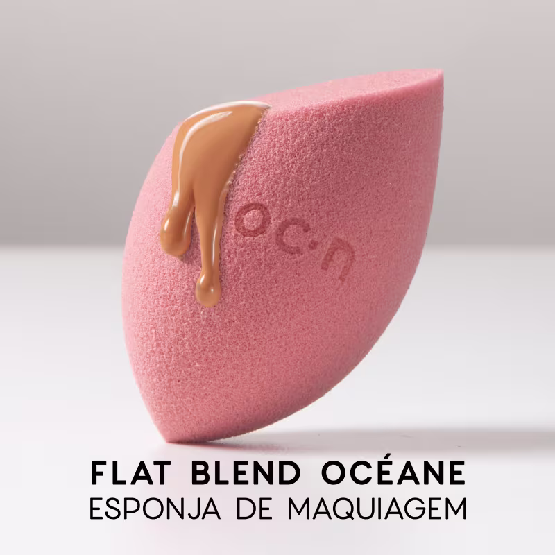 Esponja de maquiagem de cor rosa, com formato assimétrico e textura macia, com o logotipo "O.C.N." impresso na superfície.