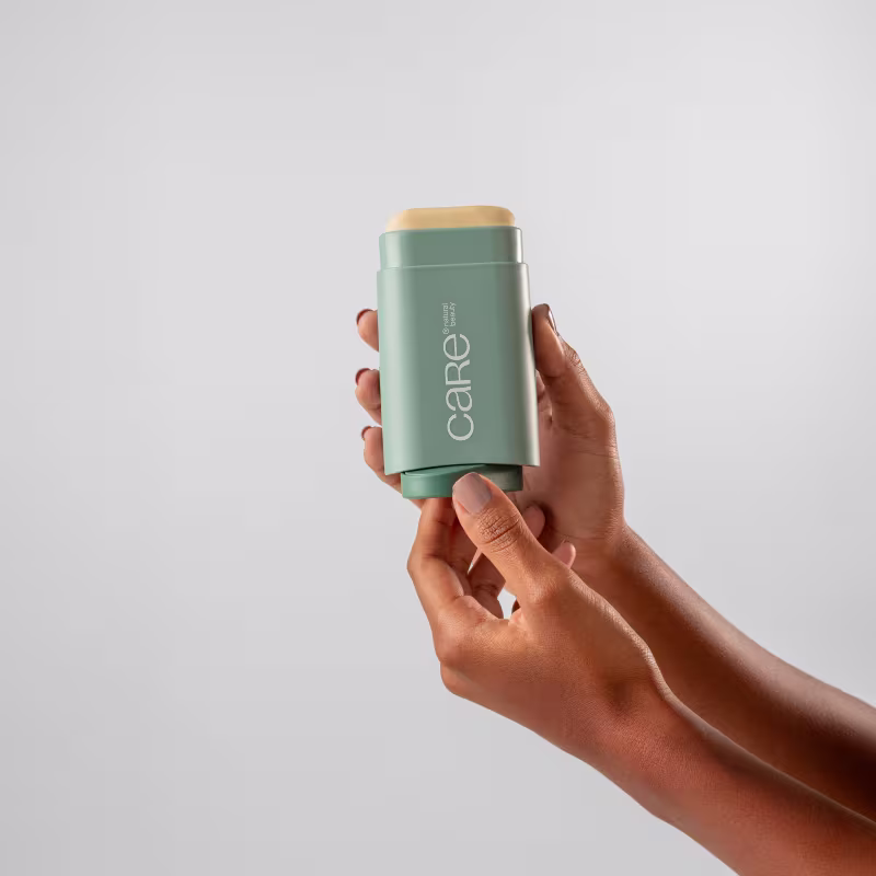 Imagem de um produto de beleza da marca Care, em um recipiente verde-menta compacto e portátil, sendo segurado por mãos em um fundo branco, sugerindo um ambiente minimalista e moderno.