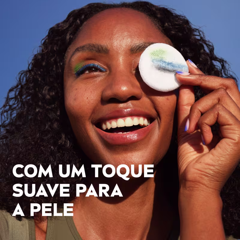 Mulher sorridente segurando um aplicador de maquiagem branco com texto "Com um toque suave para a pele" em português.