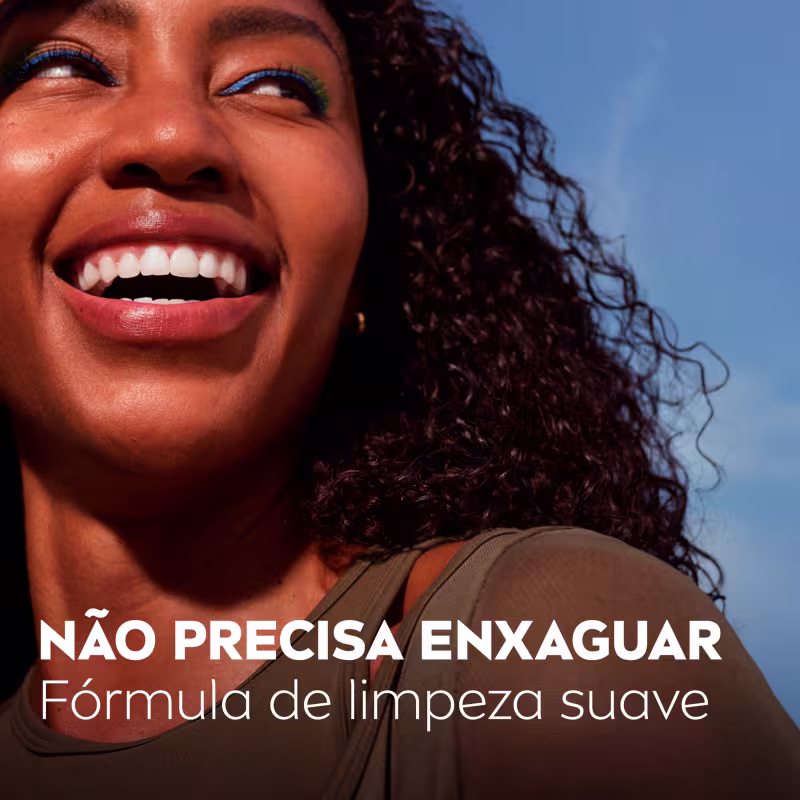 Mulher com cabelos cacheados sorri amplamente, exibindo uma fórmula de limpeza suave da marca NIVEA.
