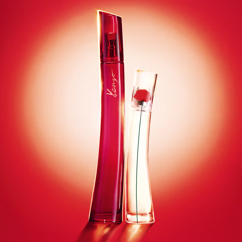 Dois itens de perfumaria em fundo vermelho-alaranjado. Um frasco vermelho com rótulo  e outro frasco transparente com líquido transparente. Ambos os frascos têm formas elegantes e design moderno.