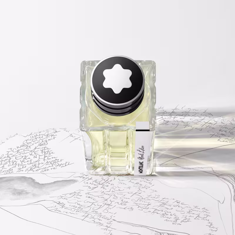 Frasco de perfume Montblanc com tampa preta e logotipo em forma de estrela. Embalagem de vidro transparente com líquido amarelo claro. Rótulo preto com texto "Montblanc" em destaque.