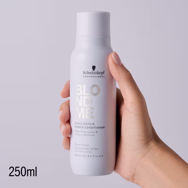 Produto de condicionador da marca Schwarzkopf Professional em embalagem branca com detalhes em roxo, sendo segurado por uma mão em fundo branco.