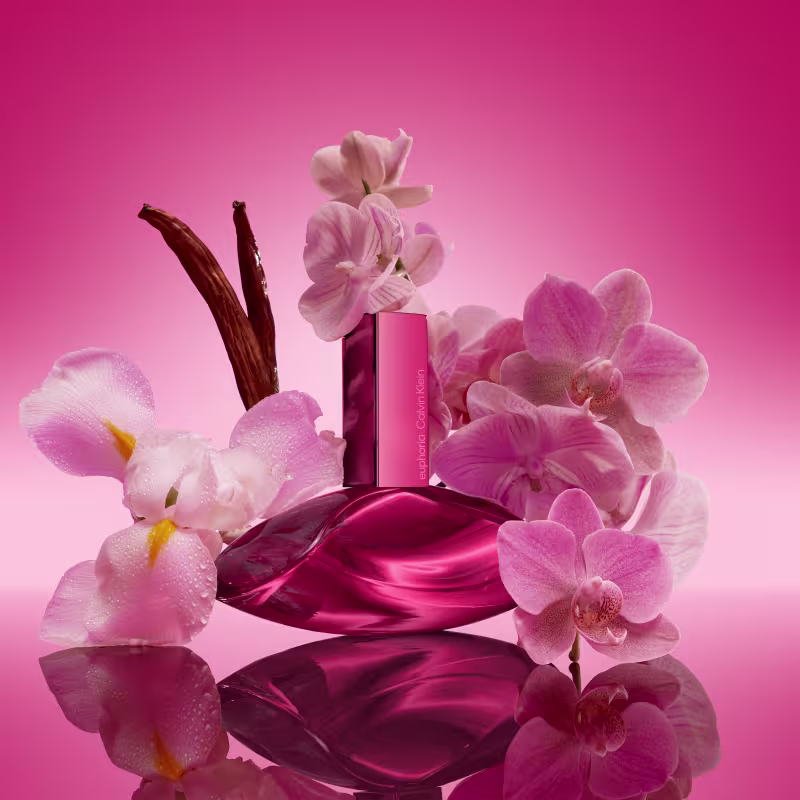 Um item de perfumaria em formato de frasco com tampa, em tons de rosa brilhante. O frasco possui uma forma arredondada e elegante, com um rótulo destacado na parte frontal exibindo o nome da marca em letras brancas.