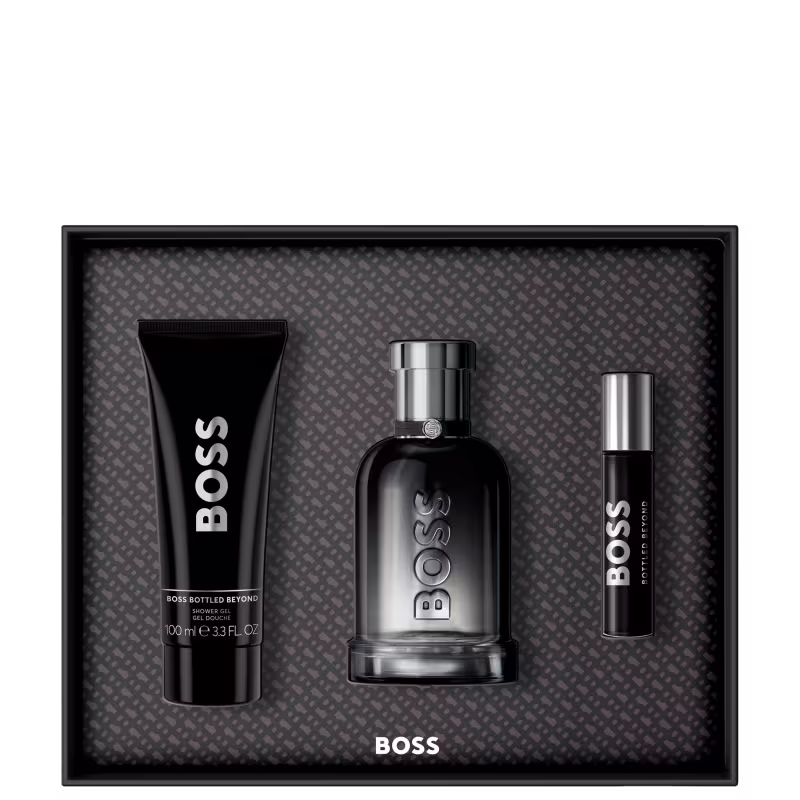 Conjunto de produtos de beleza da marca Boss, incluindo um frasco de perfume preto, um tubo de gel de banho preto e um frasco de perfume em tamanho mini. Os produtos apresentam design moderno e elegante, com predominância de cores pretas e cinzas.