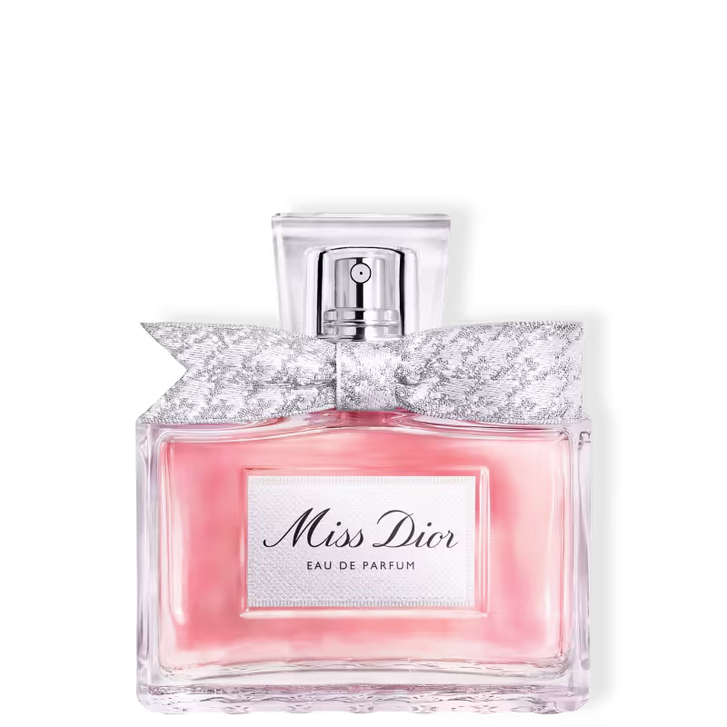 Frasco de perfume Miss Dior em formato retangular com tampa prateada. Embalagem com detalhes em renda branca e rosa claro, com texto "Miss Dior Eau de Parfum" em destaque.