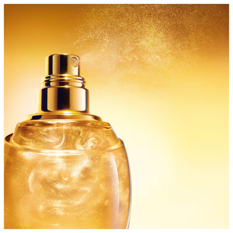 Frasco de perfume para cabelo Dior em formato de gota, com corpo dourado e detalhes em fios dourados entrelaçados, tampa transparente redonda. Embalagem elegante e sofisticada.