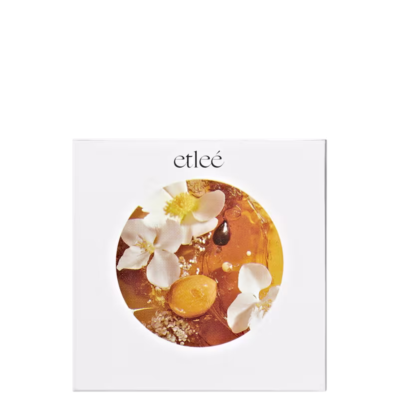 Caixa branca com logotipo Etleé e imagem circular  com flores brancas, gotas douradas de caramelo e pistache sugerindo a composição olfativa do perfume.