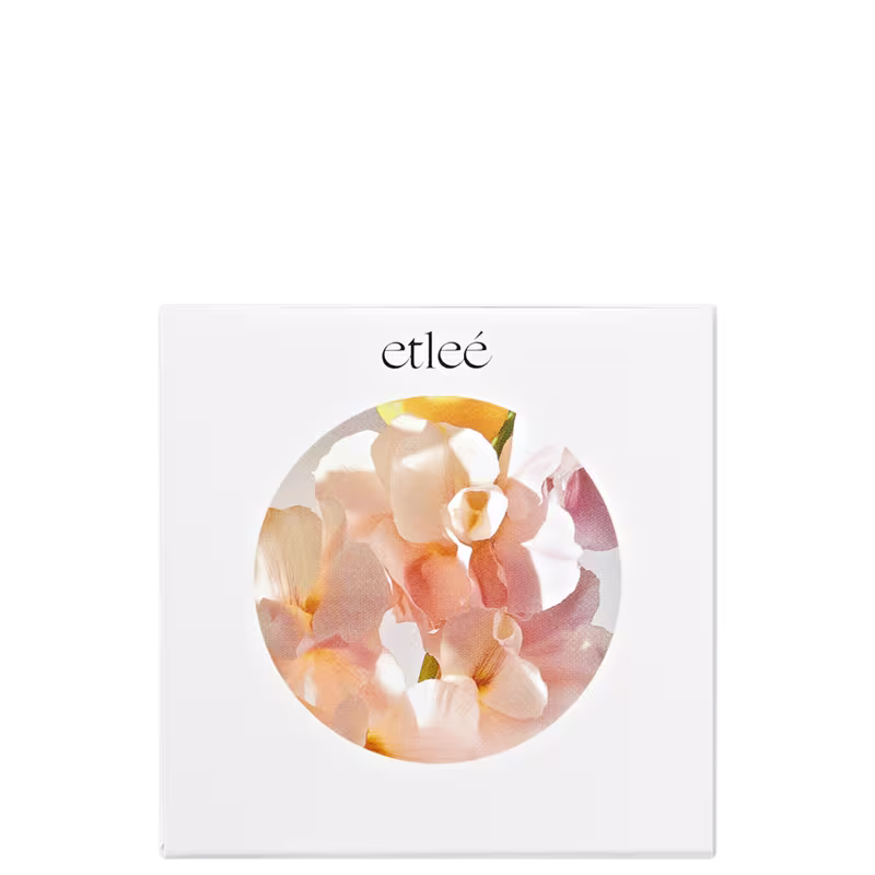Imagem circular com flores delicadas em tons de laranja e rosa, sugerindo composição olfativa do perfume