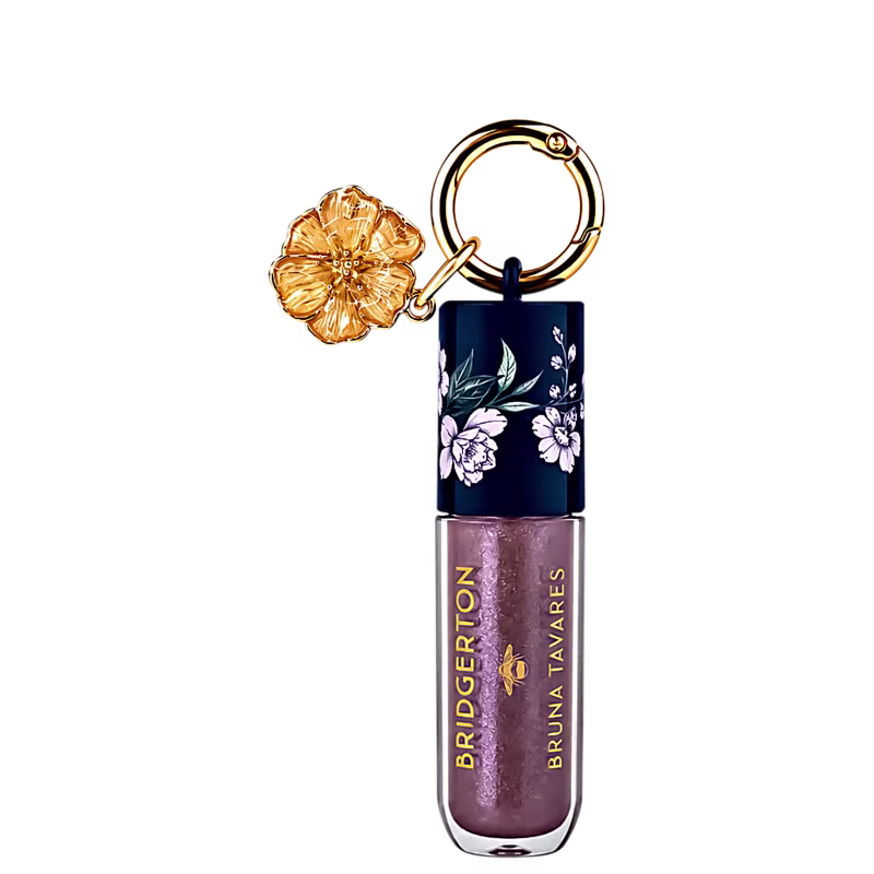 Gloss labial BT x Bridgerton da marca Bruna Tavares em embalagem cilíndrica com tampa azul-marinho com flores brancas e dourada, acompanhado de pingente floral dourado.