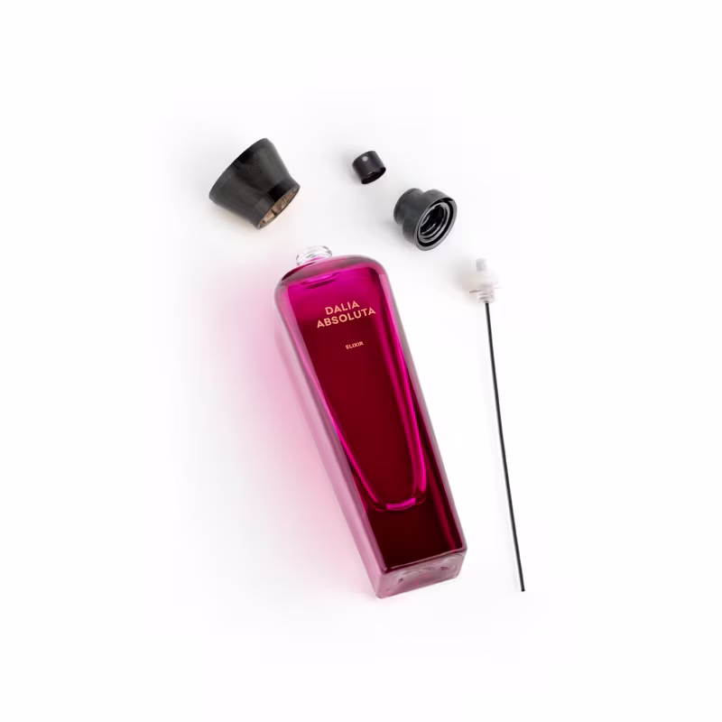 Frasco de perfume Dalia Absoluta da marca Adolfo Dominguez, com embalagem de vidro rosa vibrante. Ao lado aplicador e tampa do produto.