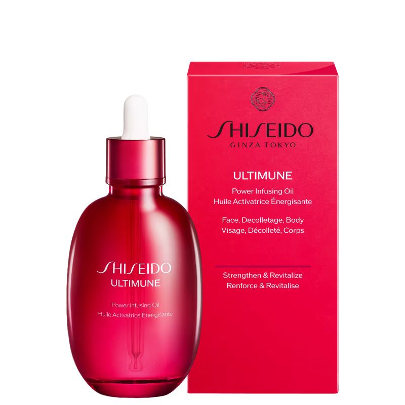 Frasco de vidro vermelho contendo óleo ativador de energia da marca Shiseido, com caixa vermelha e texto em inglês e francês descrevendo o produto para rosto, decote e corpo.