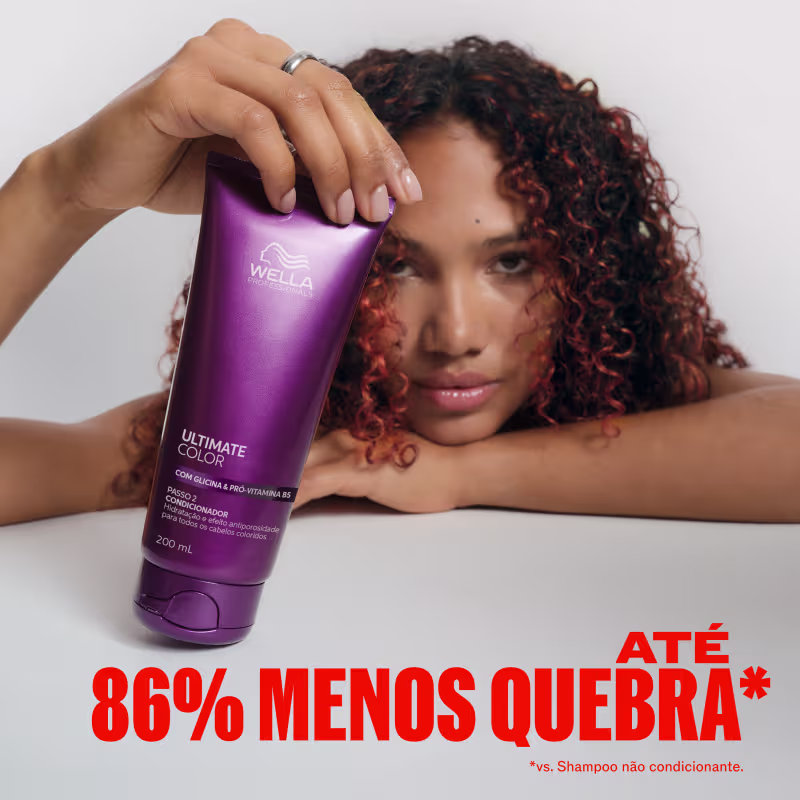 A modelo com cabelos cacheados segura um frasco roxo da linha Ultimate Color da Wella Professionals, destacando o benefício de 86% menos quebra em comparação ao uso de shampoo não condicionante.