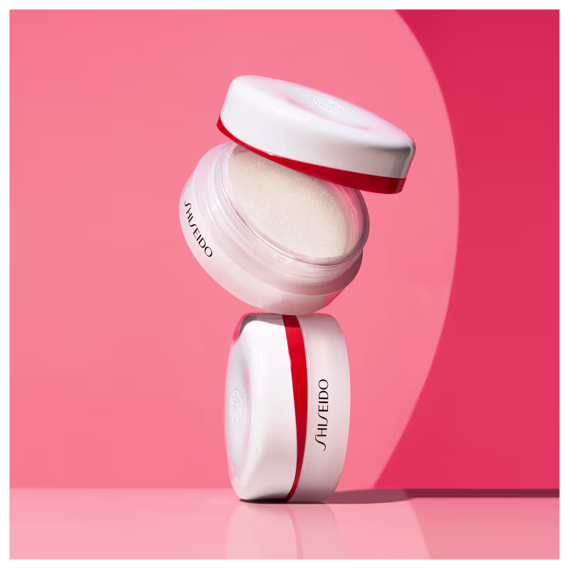 Pote branco e vermelho de item de perfumaria da marca Shiseido, com tampa e rótulo em destaque, sobre fundo rosa.