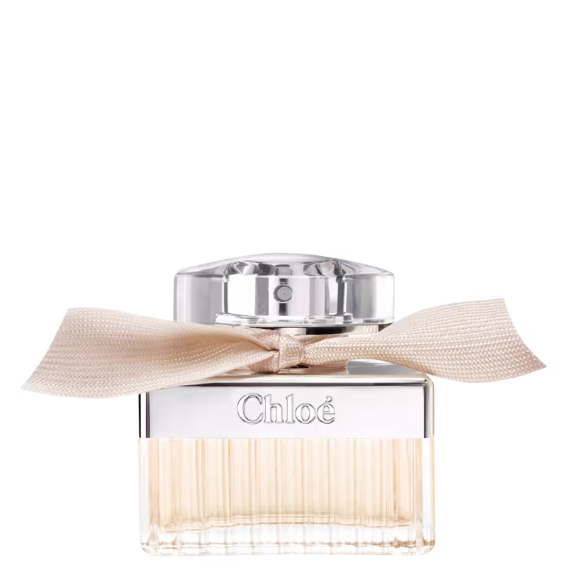 Frasco de perfume Chloé com tampa de metal e laço bege. Embalagem de vidro transparente com rótulo em relevo com o nome da marca. Produto de beleza com design elegante e sofisticado.