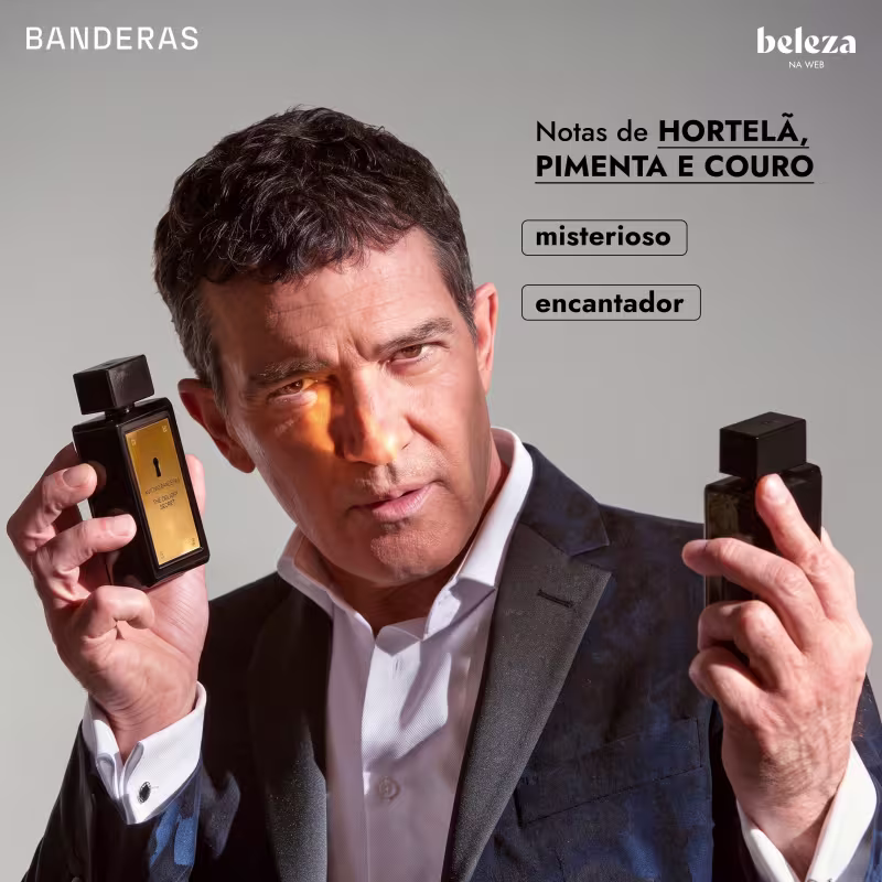 O ator Antonio Banderas segurando dois frascos de item de perfumaria da marca Banderas, com rótulos indicando "Notas de Hortelã, Pimenta e Couro" e descrevendo-os como "misterioso" e "encantador".
