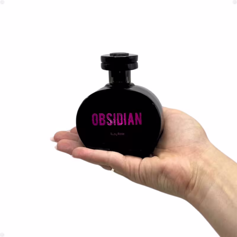 A imagem mostra uma mão segurando o Desodorante Colônia Ruby Rose Obsidian