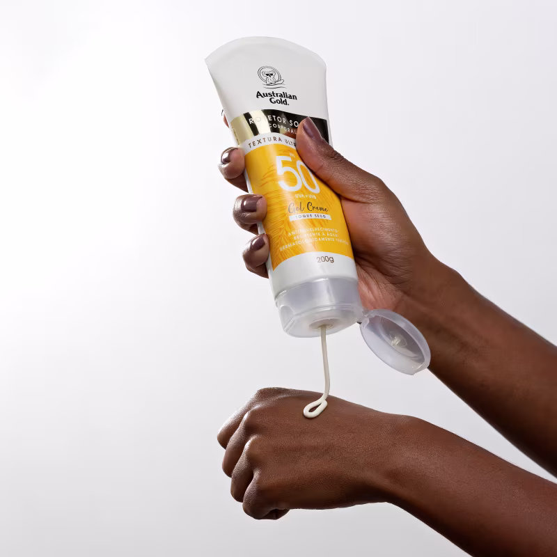 Mãos aplicam o produto nos braços.