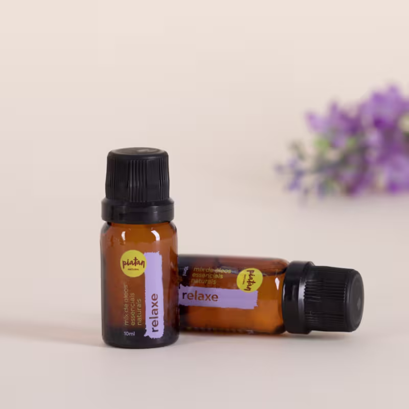 Dois frascos de vidro âmbar contendo óleos essenciais com a etiqueta "relaxe".  Ao fundo, há flores de lavanda, criando um ambiente relaxante e natural para os produtos de aromaterapia.