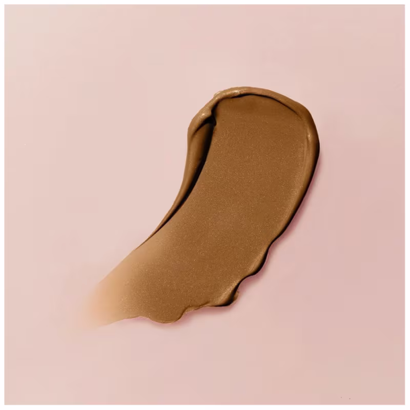 A textura do produto de beleza apresenta uma consistência cremosa e brilhante, com uma coloração dourada que sugere uma textura suave e sedosa. A aparência do produto indica uma formulação rica e hidratante.