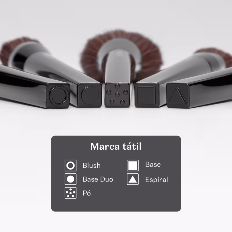 A imagem mostra que os pincéis da linha possuem marca tátil na base, indicando sua finalidade. Círculo vasado blush, circulo cheio base duo, pontinhos pó, quadrado base e triângulo espiral.