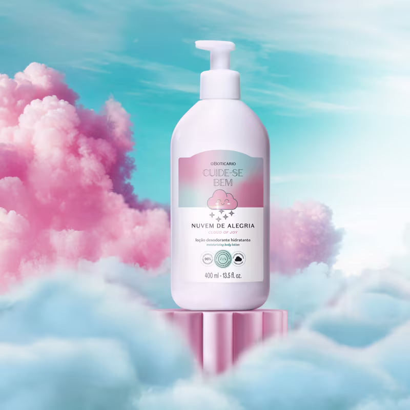 O rótulo possui uma ilustração de uma nuvem rosa e detalhes em azul claro. O frasco está posicionado em um cenário com nuvens rosa e azul, criando uma atmosfera leve e alegre.