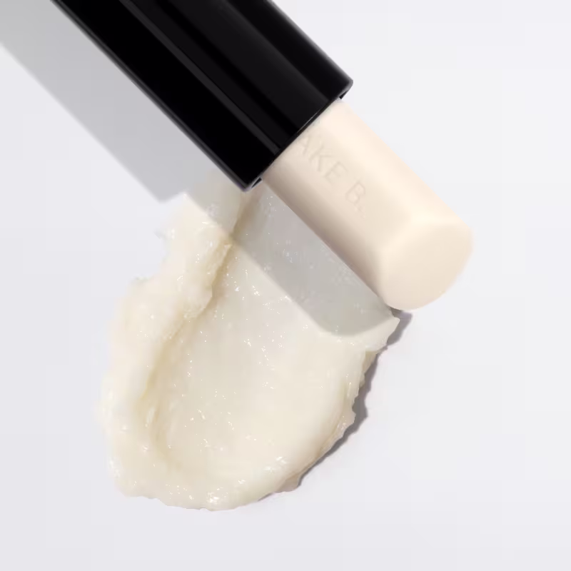 O produto de beleza apresenta uma textura cremosa, de aparência suave e brilhante, com uma coloração branca leitosa. Sua consistência parece ser macia e aveludada, indicando uma fórmula hidratante e nutritiva.