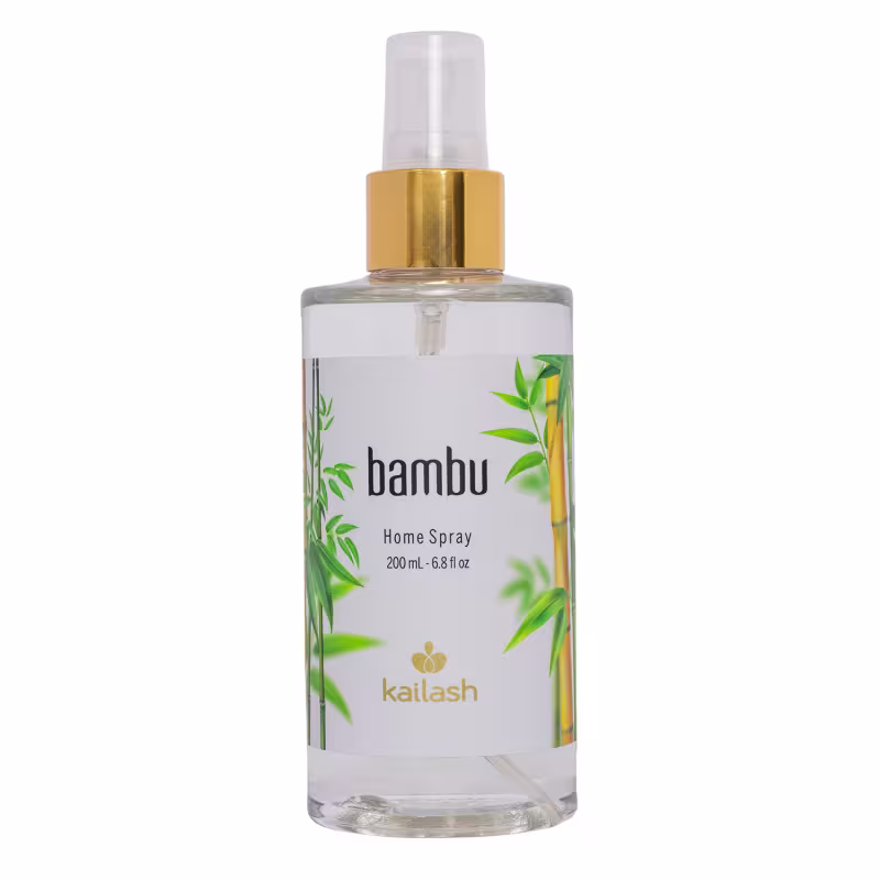 Frasco de spray para ambientes da marca Kailash, com design em tons de branco e dourado, contendo o nome "bambu" e informações sobre o volume de 200 ml. O produto apresenta uma embalagem transparente com detalhes em dourado e ilustrações de folhas verdes.