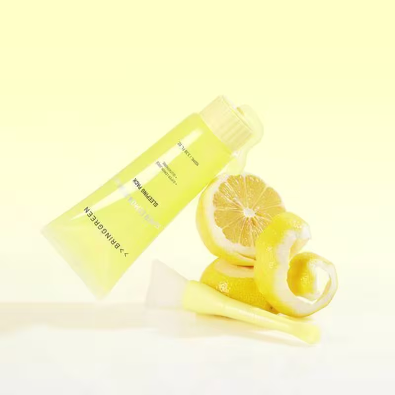 O produto de beleza da marca Bringgreen é um creme hidratante de limão, apresentado em um tubo amarelo, com fatias de limão frescas ao lado, em um ambiente claro e minimalista, sugerindo uma aplicação diária e refrescante.