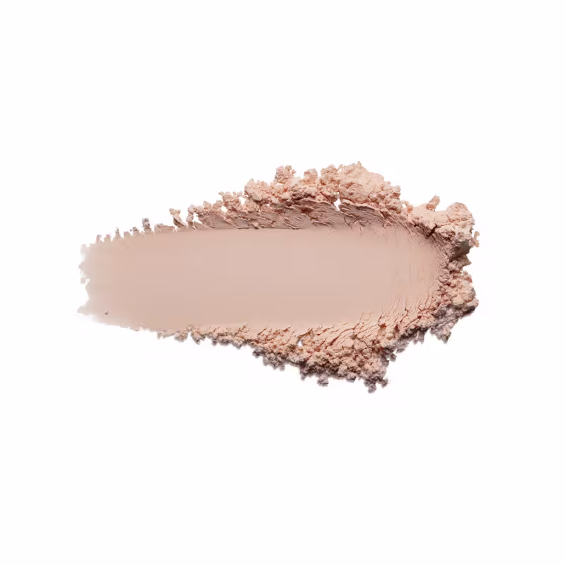 Pó compacto de maquiagem em tom bege rosado claro cor 1. O produto apresenta uma textura fina e pulverizada, formando uma superfície irregular com pequenos montes de pó solto ao redor de uma área central mais compactada.