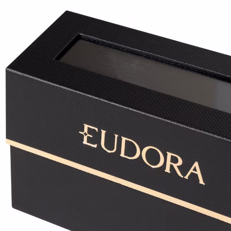 Um estojo preto elegante, com textura de couro e detalhes dourados, evoca luxo e sofisticação. Uma janela transparente revela o conteúdo precioso dentro, enquanto o nome "Eudora", em letras douradas, sugere uma marca de beleza premium.