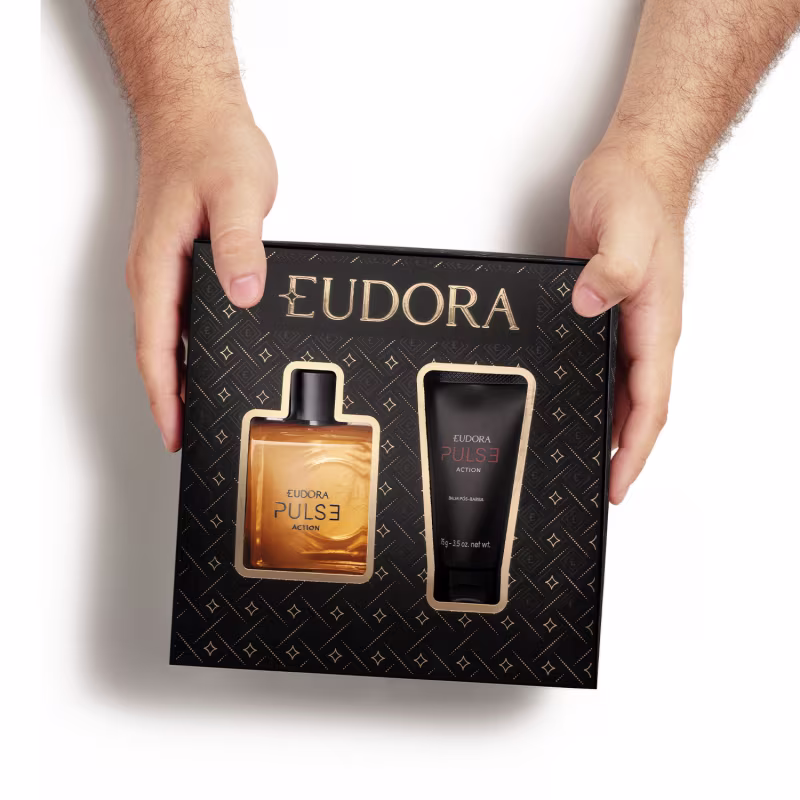 Caixa preta com o logotipo EUDORA e padrão geométrico repetido em dourado. Na sua parte frontal há a imagem do frasco de Eudora Pulse Action e do tubo do balm pós-barba.A caixa é vista de cima e é segurada pelos lados por duas mãos masculinas brancas.