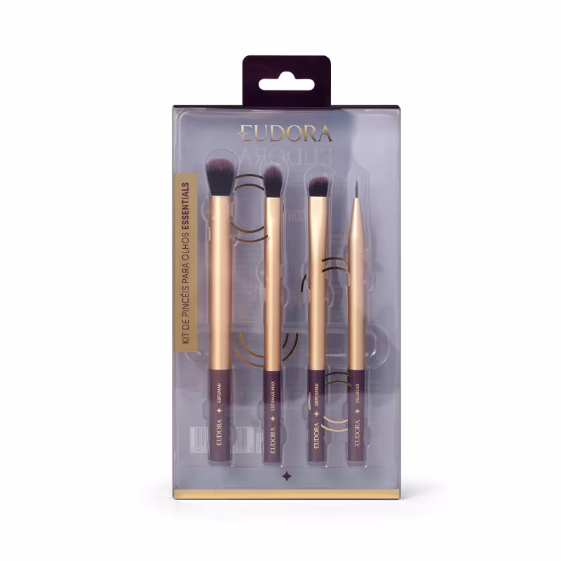 O produto é um kit de pincéis de maquiagem da marca Eudora. O kit contém 4 pincéis com cabos dourados e detalhes em preto. Os pincéis possuem diferentes formatos e tamanhos, para diferentes aplicações. A embalagem é uma caixa plástica transparente.