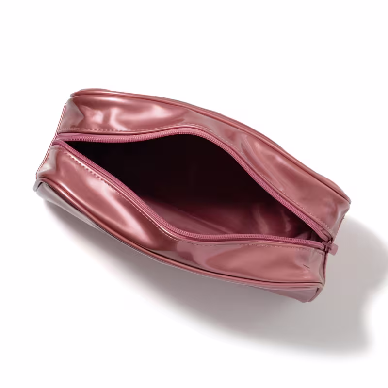 Nécessaire rosé metalizado visto de cima, mostrando o zíper aberto e compartimento interno, em formato retangular.