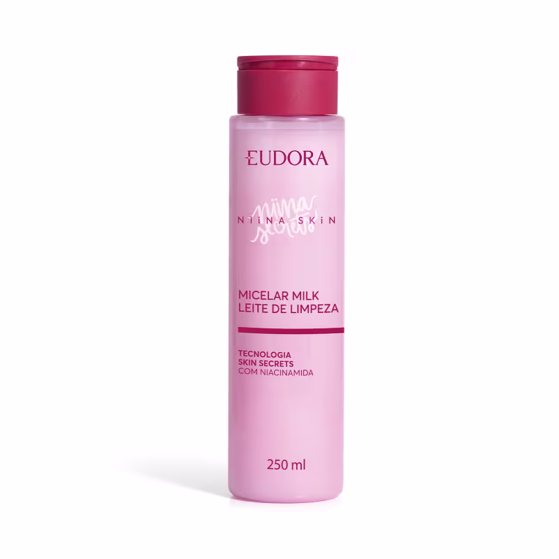 Frasco rosa de 250 ml de leite micelar da linha Niina Secrets da marca Eudora, com tampa vermelha e texto em português descrevendo o produto como "Leite de Limpeza" com tecnologia Skin Secrets com niacinamida.