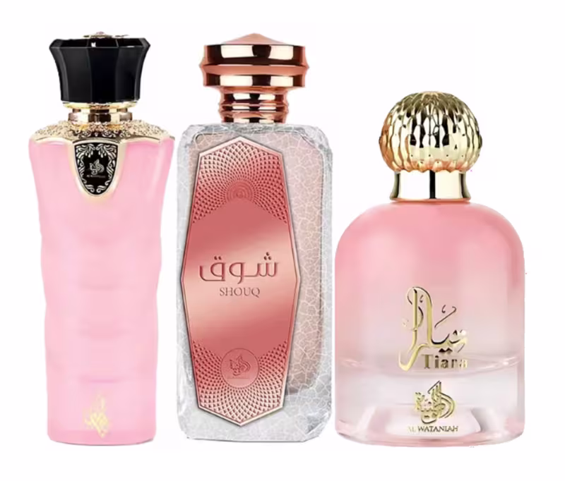 Três frascos de perfumes da marca Al Wataniah: um frasco rosa com detalhes dourados, um frasco prateado com padrão geométrico, e um frasco rosa com tampa dourada em formato de flor.