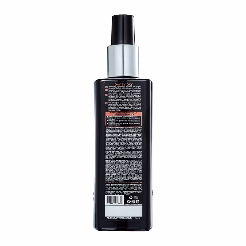 A imagem mostra um frasco plástico preto com uma tampa prateada. É um produto para cabelos chamado "Day by Day". O rótulo na parte traseira do frasco contém informações detalhadas sobre o produto, como instruções de uso, ingredientes e avisos.