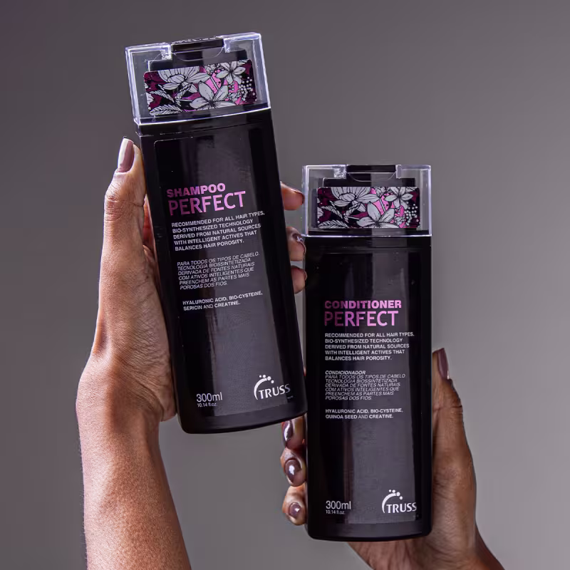 A imagem mostra Shampoo e condicionador Perfect da marca TRUSS. Embalagens plásticas pretas opacas de 300ml cada. Tampas transparentes com estampa floral rosa, branca e preta.